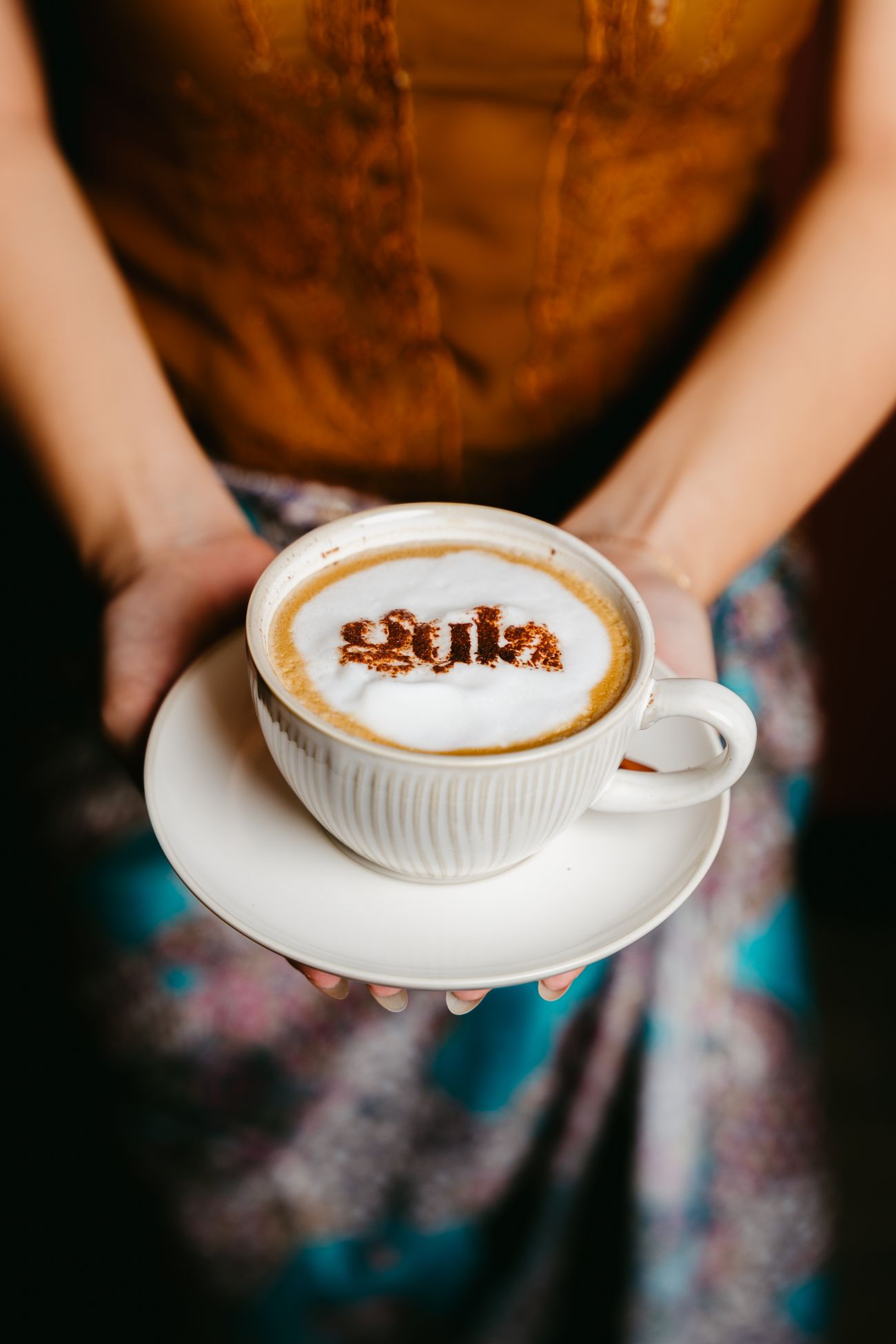 A cappuccino with latte art held in two hands